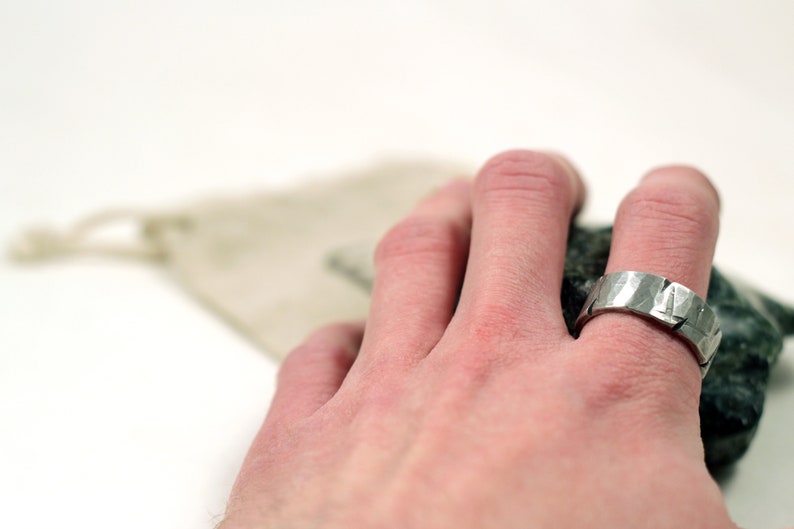 Silver pewter ring 8mm wide with hammered texture and battle damage on mans hand