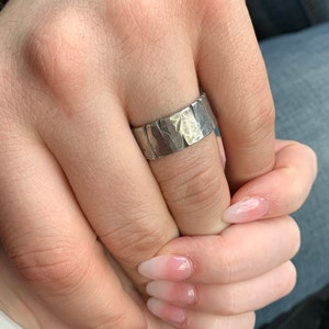 Woman holding mans hand wearing silver pewter Viking ring with battle damage. The band is 10mm wide