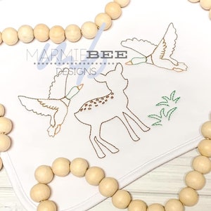 May include: Embroidered design featuring a brown deer with white spots, a green duck flying towards it, and green grass. The design is stitched on a white fabric with the text "MARMIE BEE DESIGNS" in brown.