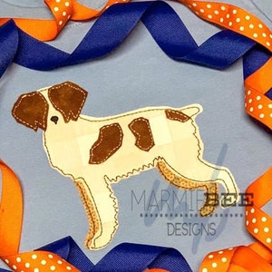 May include: A brown and white patchwork dog applique on a blue fabric background. The dog is standing with its head turned to the left. The fabric is surrounded by orange and blue ribbon.