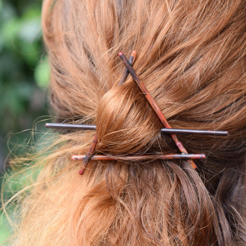 May include: A close-up of a woman's hair with a brown and black hair clip in the shape of a triangle.