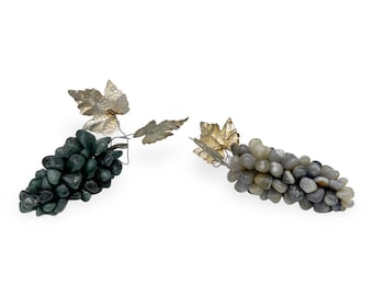 May include: Two grape clusters made of stones with gold leaf accents. One cluster is green and the other is gray.