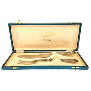May include: A teal blue velvet box with a gold latch, containing a silver knife and fork with ornate handles. The box is labeled "Argenteria Orologeria Gioielleria Russo Irvine Via Borgon 104 - 12030 Turin"