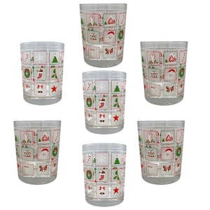 Può includere: Set di sei bicchieri di vetro trasparente con un design a tema natalizio. Ogni bicchiere presenta un diverso motivo natalizio rosso e verde con immagini di fiocchi di neve, bastoncini di zucchero, alberi di Natale e altri elementi festivi.