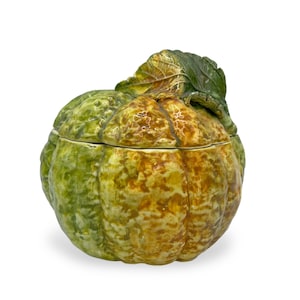 May include: A ceramic pumpkin-shaped lidded dish with a green and yellow glaze. The lid has a sculpted leaf on top.