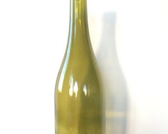 Puede incluir: Una botella de vino de vidrio verde, vacía y alta, con un tapón de corcho.