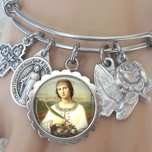 May include: A silver charm bracelet with multiple charms, including a cross, a rose, a dove, and a round charm with a picture of a saint. The bracelet is expandable and has a spring clasp.