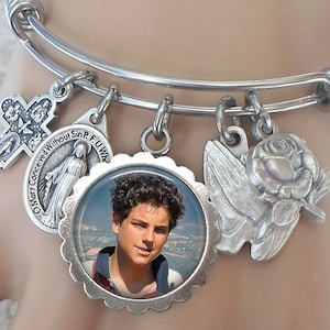 Puede incluir: Pulsera de plata con un dije de foto, un dije de cruz, un dije de rosa, un dije de paloma y un dije con las palabras "Oh María concebida sin pecado, ruega por nosotros".