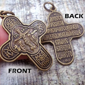 May include: A bronze cross pendant with a depiction of Jesus Christ on the front and Cyrillic text on the back. The text on the back reads "Да воскреснет Бог, и разбегутся врази его, и да обратятся от лица его ненавидящие его".