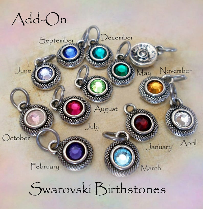 Puede incluir: Una colecci&oacute;n de dijes de piedras de nacimiento Swarovski con engastes de metal plateado. Cada dije presenta una piedra preciosa de diferente color, con los meses etiquetados alrededor. El texto "Add-On" y "Swarovski Birthstones" tambi&eacute;n es visible.