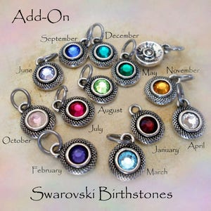 May include: Twelve silver charms with a crystal birthstone for each month of the year. The charms are labeled with the month name and are arranged in a circle. The text "Add-On" and "Swarovski Birthstones" are also visible.