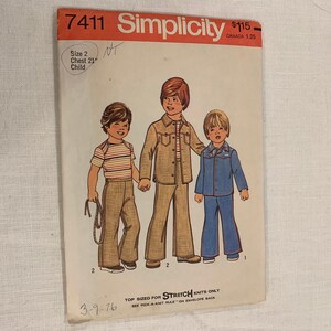 Könnte beinhalten: Vintage Simplicity Schnittmuster 7411 für Kinderkleidung. Das Muster zeigt Illustrationen von drei Kindern in Outfits, darunter ein gestreiftes Hemd, eine Jacke und Jeans-Outfits. Das Muster ist Größe 2, Brustumfang 53 cm, und datiert vom 3.9.76.