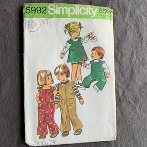 Puede incluir: Patrón de costura Simplicity 5992 vintage para ropa de niño pequeño. La portada presenta ilustraciones de niños con monos y vestidos. El patrón incluye tallas 1/2 y pecho 19. Con fecha del 22 de noviembre del 74.