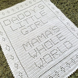 K&ouml;nnte beinhalten: Wei&szlig;e geh&auml;kelte Babydecke mit dem Text "Happy Baby" und "Made with Love" in einer dekorativen Schrift.