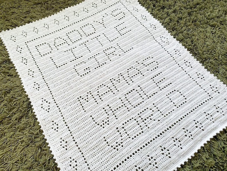K&ouml;nnte beinhalten: Wei&szlig;e geh&auml;kelte Babydecke mit dem Text "Happy Baby" und "Made with Love" in einer dekorativen Schrift.