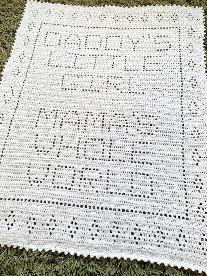 K&ouml;nnte beinhalten: Wei&szlig;e geh&auml;kelte Babydecke mit den Worten "Baby's First Year" und "Mommy's Little Angel" in einer dekorativen Schrift.