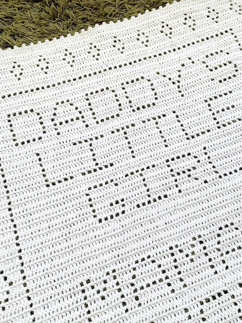 K&ouml;nnte beinhalten: Wei&szlig;e H&auml;keldecke mit einem sich wiederholenden Muster aus kleinen Kreisen. Die Decke hat einen zarten, durchbrochenen Look.