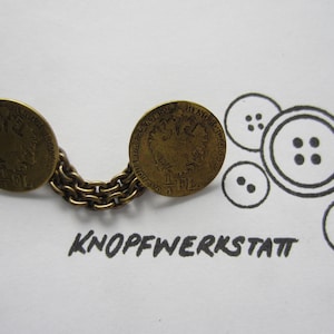 May include: Two antique gold-toned coin buttons connected by a chain. The coins feature an eagle design and the text "K.K.  OESTERREICH  1781". The image also includes a drawing of buttons.