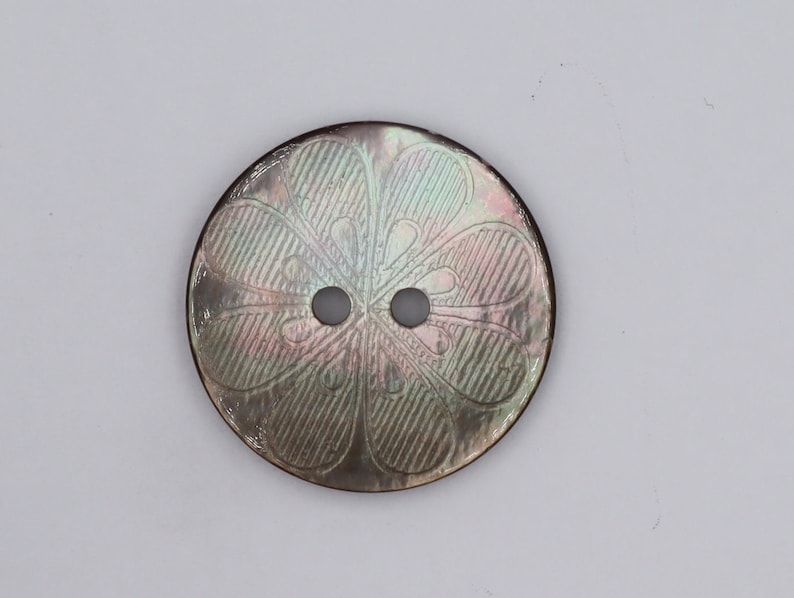 May include: A two-hole iridescent mother of pearl button with a floral design.