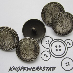 May include: Four silver-toned buttons with a raised design of a bird with outstretched wings. The buttons have the text "FRANCOFURTI. AD NORMAM CONVENTIONIG X.E.F. MARK" around the edge.