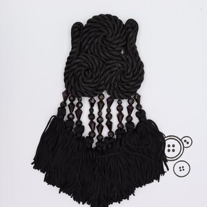 May include: Black tassel trim with a large, black, rope-like embellishment and dark purple beads.
