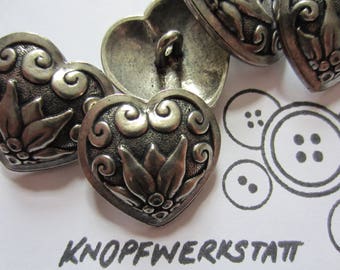 May include: Four silver heart-shaped buttons with intricate floral designs. The buttons have a slightly aged, antique look.