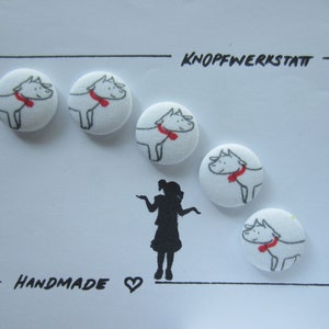 Könnte beinhalten: Fünf weiße Stoffknöpfe mit einer schwarzen und roten Illustration eines Hundes mit Schal. Die Knöpfe sind in einem Halbkreis angeordnet, darunter der Text "KNOPFWERKSTATT" und "HANDMADE".