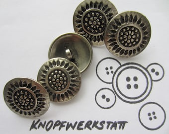 May include: Four silver metal buttons with a decorative floral design. The buttons have a raised center with a smaller floral design. The buttons are arranged in a semi-circle on a white background.