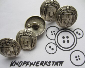 May include: Four silver-toned buttons with a coat of arms design. Each button features a crown, a shield with a checkered pattern, and a pair of wings. The buttons are arranged in a semi-circle on a white background.