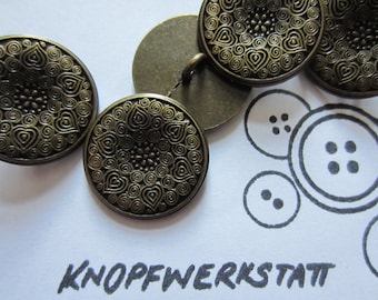 Op de afbeelding: Een set van vier antiek ogende bronzen knopen met ingewikkelde, draaiende patronen. De knopen zijn rond en hebben een verhoogd ontwerp. De knopen zijn in een rij gerangschikt, met de tekst "KNOFFWERKSTATT" zichtbaar eronder.