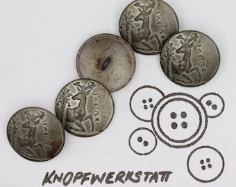 May include: Five antique silver-toned buttons with a deer design and the word "Jaegle" inscribed on each. The buttons are arranged in a semi-circle on a white surface. A drawing of four buttons with different numbers of holes is below the buttons.