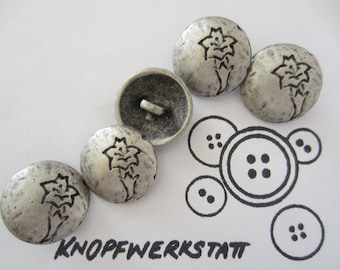 May include: Silver-toned metal buttons with a floral design and a distressed finish. The buttons are round and have a shank on the back. The image also includes a drawing of various button styles and the text "KNOPFWERKSTATT".