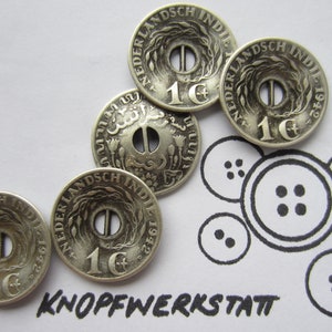May include: Close-up of several vintage silver buttons with a central hole and the text "NEDERLANDSCH INDIE 1942 1¢". The image also includes a drawing of buttons and the text "KNOPFWERKSTATT".