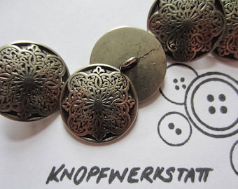 May include: Four ornate metal buttons with a decorative floral design. The buttons are in shades of gold and silver.