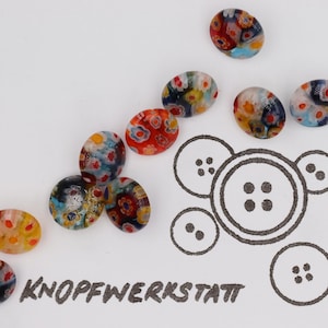 Könnte beinhalten: Ovale Glas Knöpfe mit bunten Blumenmustern in Rot, Gelb und Blau. Die Knöpfe liegen auf weißem Grund, zusammen mit einer Skizze eines Knopfes und dem Text "KNOPFWERKSTATT".