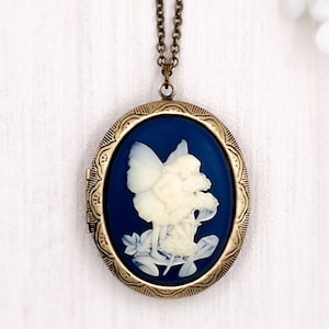 May include: A gold oval locket necklace with a blue enamel background and a white cameo of a fairy with wings holding a flower.