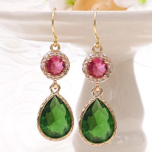 Peut inclure: Boucles d'oreilles pendantes dorées avec une pierre ronde rose entourée de petites pierres claires et une pierre verte en forme de larme.