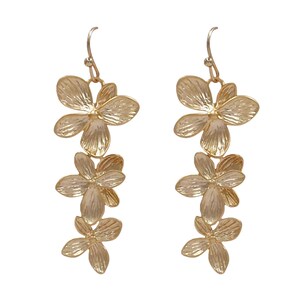 May include: A pair of gold-colored floral drop earrings. Each earring features three flower-shaped pendants, with detailed petal textures. The earrings hang from a simple hook design, suitable for pierced ears. The background is plain white.