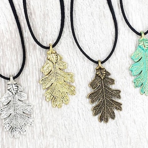 May include: Four necklaces with oak leaf pendants in silver, gold, bronze, and turquoise. Each necklace has a black suede cord.