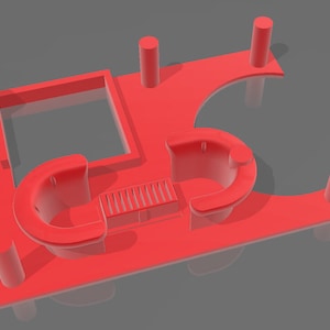 Puede incluir: Un objeto rojo impreso en 3D con una abertura rectangular, secciones curvas y soportes cilíndricos. El diseño incluye una serie de líneas paralelas y formas redondeadas, todo en color rojo sólido. El objeto está sobre un fondo gris.