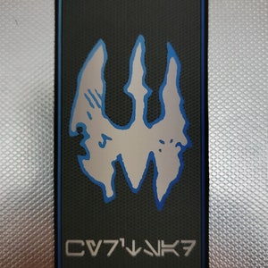 Könnte beinhalten: Ein schwarzer und blauer Patch mit einem weißen stilisierten Symbol und dem Text "CV71NK7".