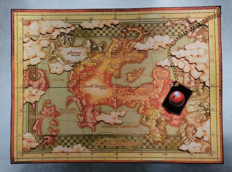 May include: A vintage-style map with a gold chain and a red and black charm hanging from it. The map is titled "Endymion" and features various landmasses and islands, including "Death Triangle" and "The Sands of Winter".