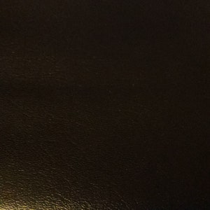 May include: A black leather-bound book with a textured surface.