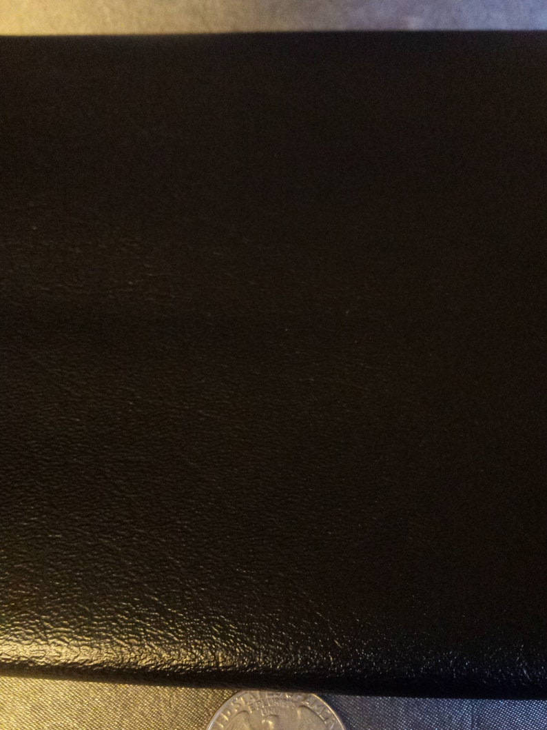May include: A black leather-bound book with a textured surface.
