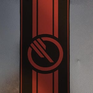 Puede incluir: Bandera rectangular negra y roja con un emblema circular. La bandera presenta una franja roja central flanqueada por franjas negras. El emblema es un círculo negro con tres líneas diagonales. Dos remaches negros en la parte superior.