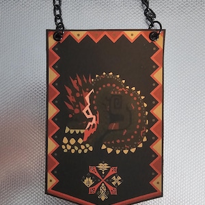 May include: A black banner with a red and yellow border and a stylized image of a red and black monster with a chain hanging from the top.