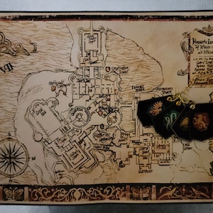 May include: A vintage-style map of Hogwarts School of Witchcraft and Wizardry, with a gold chain and four house crests hanging from it. The crests are Gryffindor, Slytherin, Hufflepuff, and Ravenclaw.
