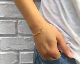 May include: A gold chain bracelet with a delicate four-leaf clover charm.