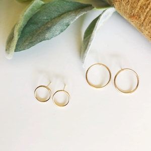 May include: A set of four gold-toned hoop earrings. Two of the hoops are smaller and two are larger.