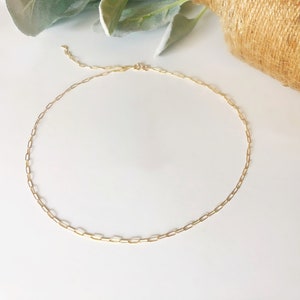 May include: A gold chain necklace with a delicate, linked chain design. The chain is made of small, oval-shaped links.